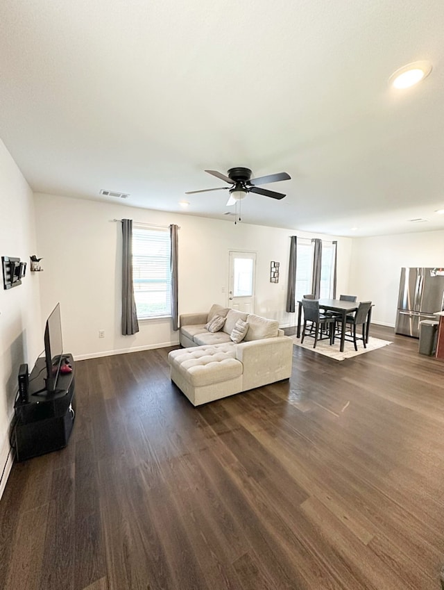 living room featuring dark wood-type flooring and ceiling fan