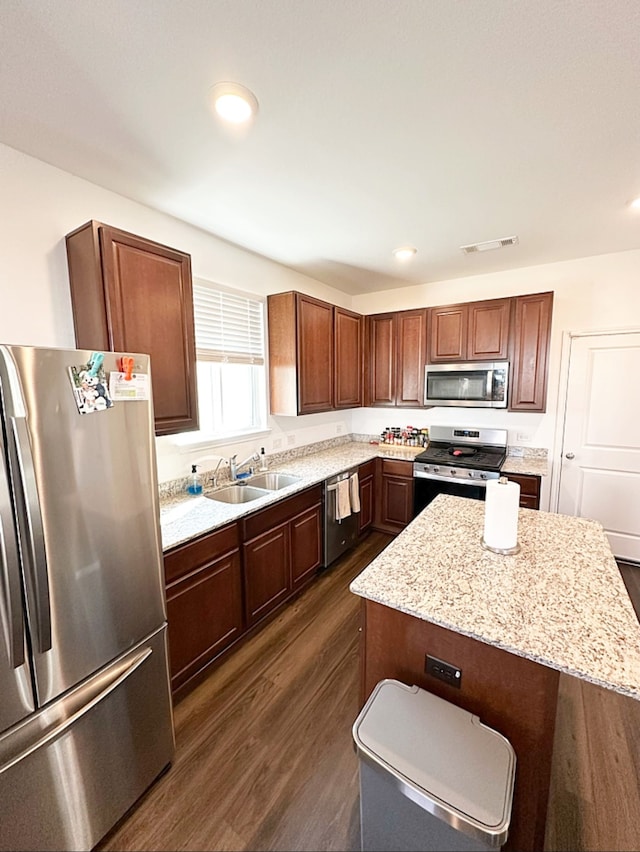 kitchen with dark wood-type flooring, sink, a kitchen island, and appliances with stainless steel finishes