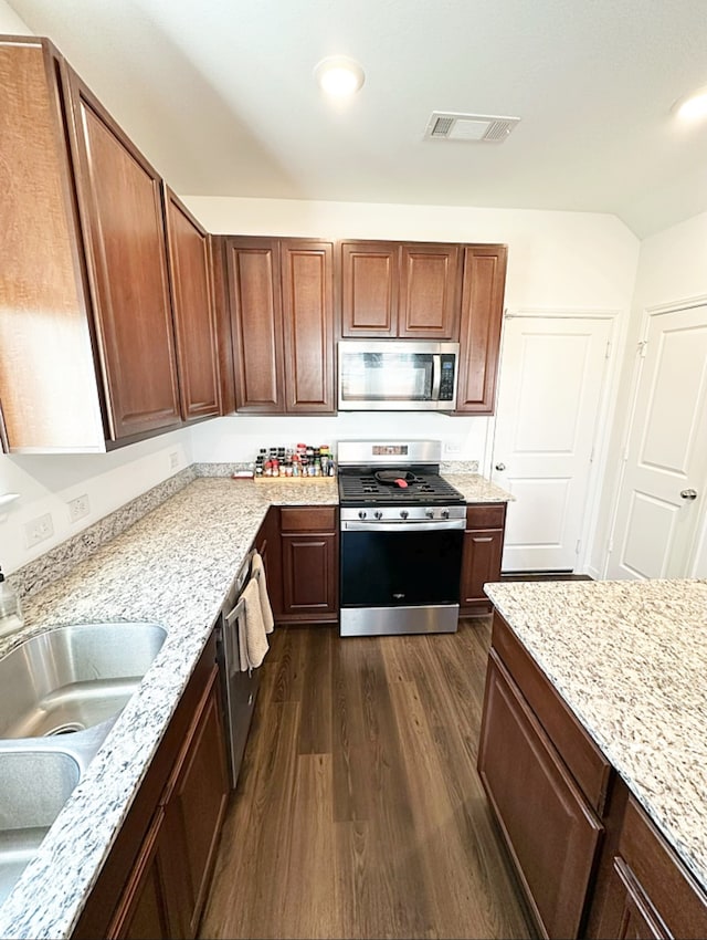 kitchen featuring appliances with stainless steel finishes, light stone counters, dark hardwood / wood-style floors, and sink