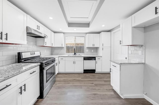 kitchen featuring light stone countertops, stainless steel gas stove, white cabinets, light wood-type flooring, and dishwasher