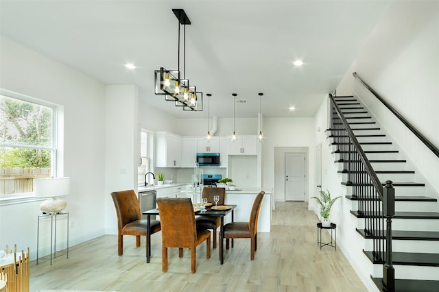 dining space with light hardwood / wood-style flooring, sink, and a chandelier