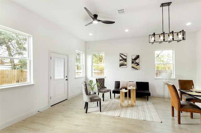 living area with a wealth of natural light, light hardwood / wood-style floors, and ceiling fan with notable chandelier