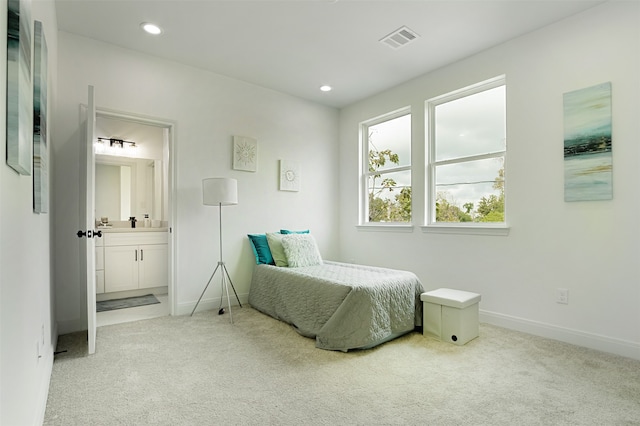 bedroom featuring ensuite bathroom and carpet flooring