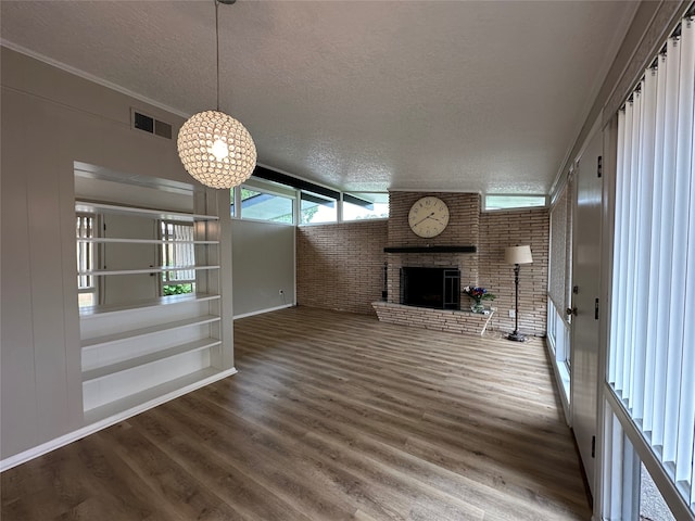 unfurnished living room featuring a brick fireplace, hardwood / wood-style flooring, a textured ceiling, and brick wall