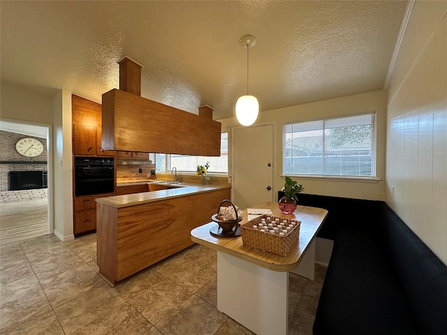 kitchen with pendant lighting, kitchen peninsula, a textured ceiling, and oven