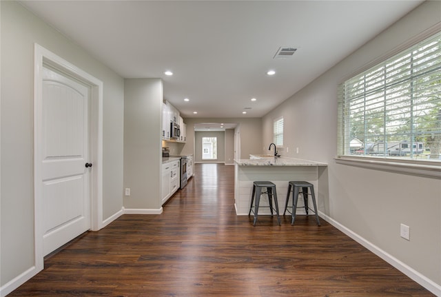 kitchen featuring a wealth of natural light, white cabinetry, kitchen peninsula, and stainless steel appliances