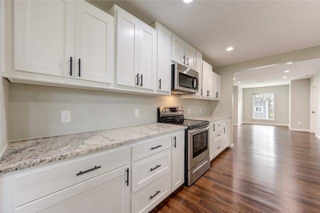 kitchen with stainless steel appliances, white cabinets, light stone counters, and dark hardwood / wood-style flooring