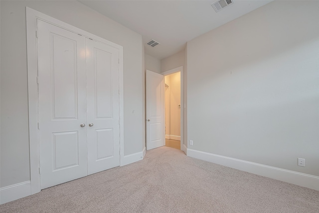 unfurnished bedroom featuring light carpet and a closet