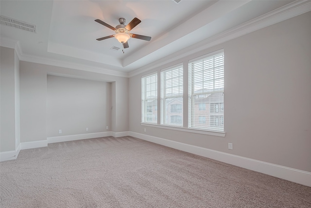 carpeted empty room with ceiling fan, a healthy amount of sunlight, a tray ceiling, and ornamental molding