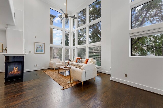 living room with dark wood-type flooring, a towering ceiling, and a wealth of natural light