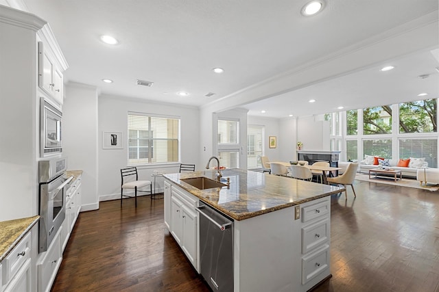 kitchen with stainless steel appliances, white cabinets, sink, and an island with sink