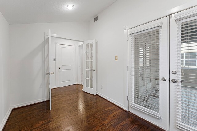 foyer entrance featuring french doors, dark wood-type flooring, a textured ceiling, and vaulted ceiling