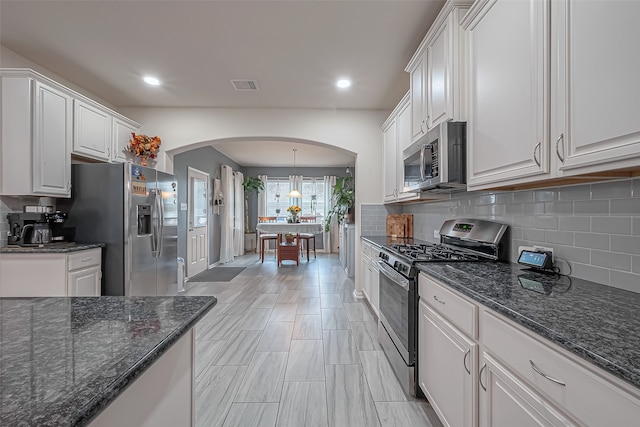 kitchen featuring appliances with stainless steel finishes, hanging light fixtures, and white cabinets