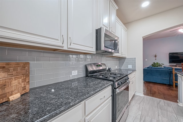 kitchen featuring white cabinets, light wood-type flooring, appliances with stainless steel finishes, and tasteful backsplash