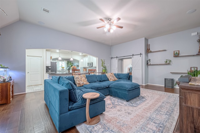 living room with a barn door, ceiling fan, lofted ceiling, and hardwood / wood-style floors