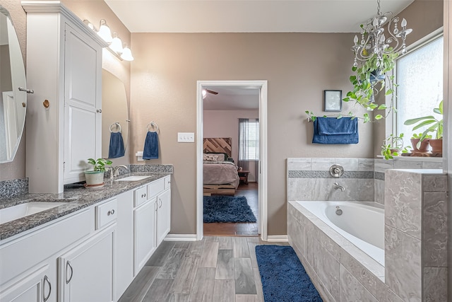 bathroom featuring vanity, tiled bath, wood-type flooring, and plenty of natural light