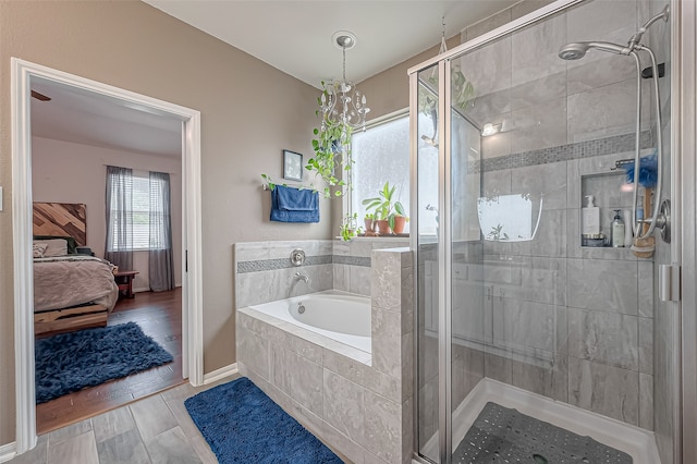 bathroom with separate shower and tub and an inviting chandelier