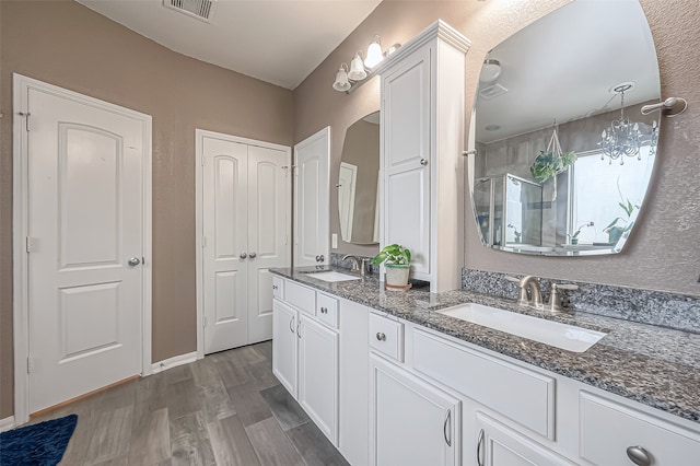 bathroom with wood-type flooring, vanity, and a shower with door