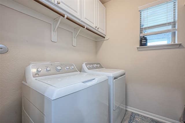 clothes washing area featuring cabinets and washing machine and clothes dryer