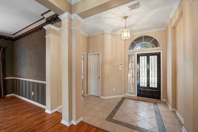 foyer entrance featuring decorative columns, light tile patterned floors, and ornamental molding