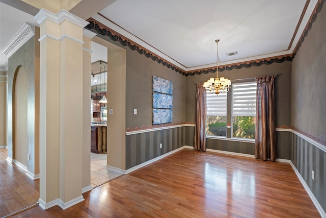 unfurnished dining area with light hardwood / wood-style floors, crown molding, and a notable chandelier