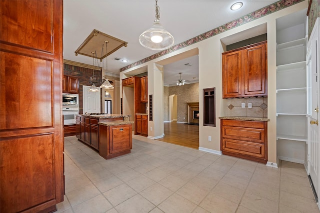 kitchen featuring pendant lighting, a center island, light stone counters, and stainless steel appliances