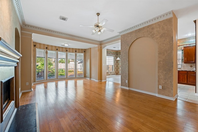 unfurnished living room with a high end fireplace, light hardwood / wood-style flooring, ceiling fan, and ornamental molding