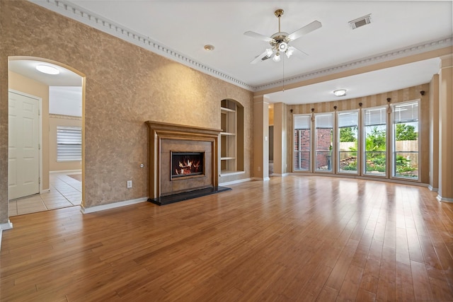 unfurnished living room with ceiling fan, light hardwood / wood-style floors, a premium fireplace, and crown molding