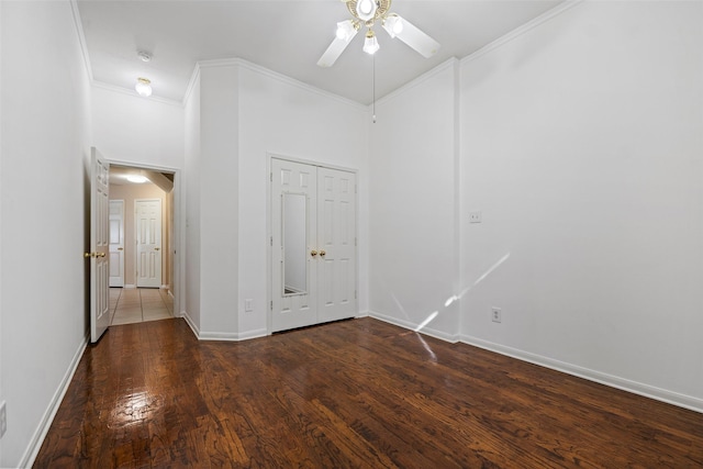 empty room featuring a high ceiling, dark hardwood / wood-style flooring, ceiling fan, and crown molding