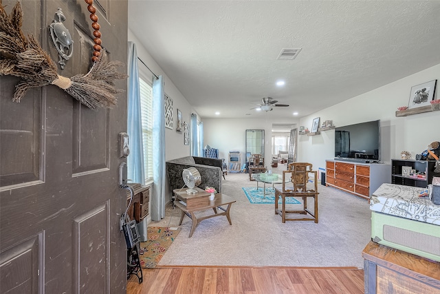 living room with a textured ceiling, hardwood / wood-style floors, and ceiling fan