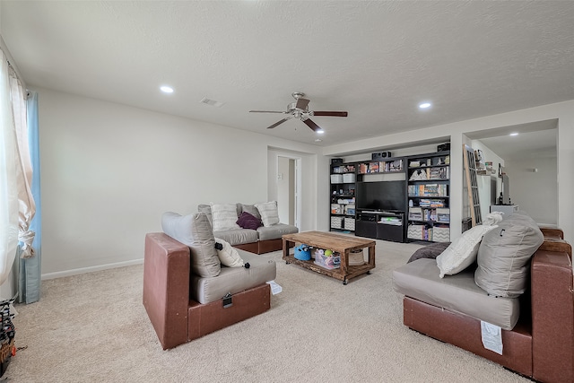 living room with a textured ceiling, light colored carpet, and ceiling fan