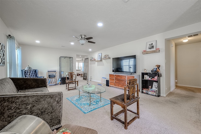 carpeted living room with ceiling fan and a textured ceiling