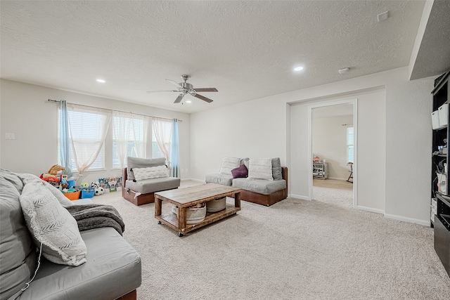 living room with ceiling fan, a textured ceiling, and light carpet