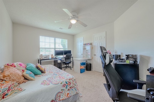 bedroom featuring a textured ceiling, light colored carpet, and ceiling fan