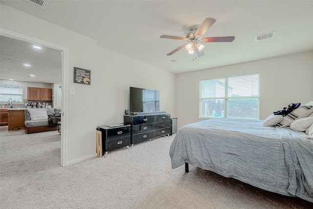 carpeted bedroom with ceiling fan, a textured ceiling, and sink