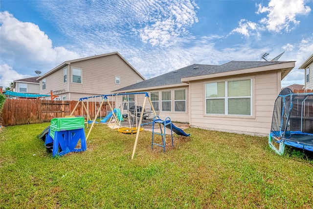 back of property featuring a playground, a yard, and a trampoline