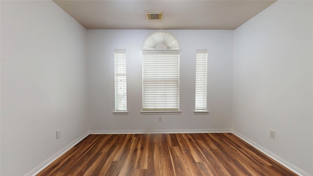 spare room with dark hardwood / wood-style floors and plenty of natural light