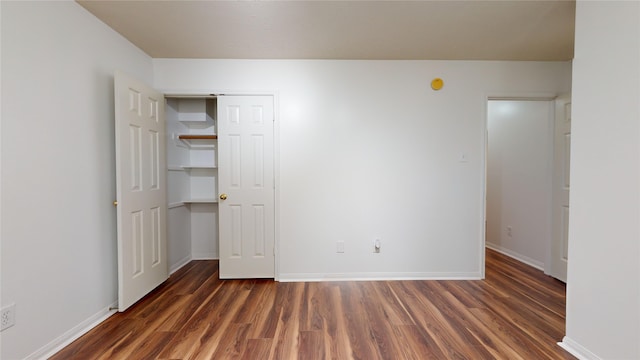 unfurnished bedroom with a closet and dark hardwood / wood-style flooring