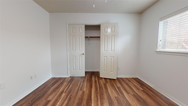 unfurnished bedroom with dark wood-type flooring and a closet