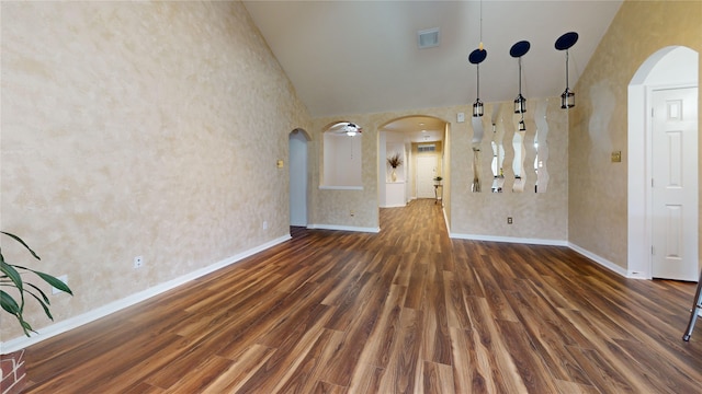 unfurnished living room featuring high vaulted ceiling and dark wood-type flooring