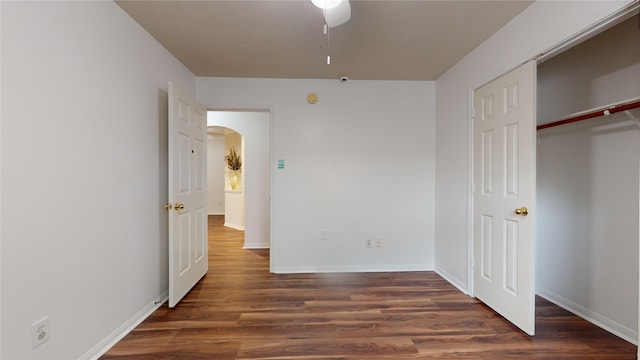 unfurnished bedroom with ceiling fan, a closet, and dark wood-type flooring