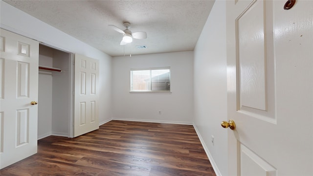 unfurnished bedroom with ceiling fan, dark wood-type flooring, and a textured ceiling