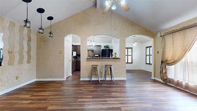 kitchen featuring kitchen peninsula, a kitchen breakfast bar, dark hardwood / wood-style flooring, and black fridge