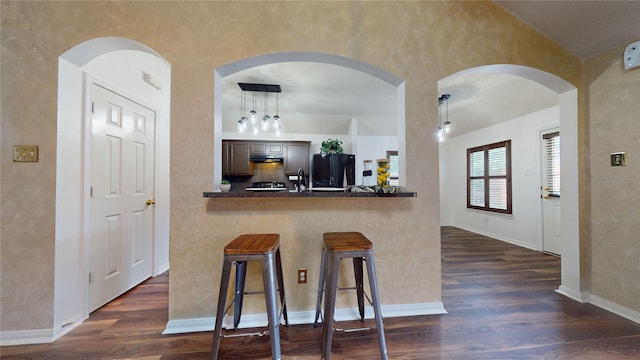 kitchen featuring dark hardwood / wood-style floors, a kitchen breakfast bar, kitchen peninsula, and decorative light fixtures