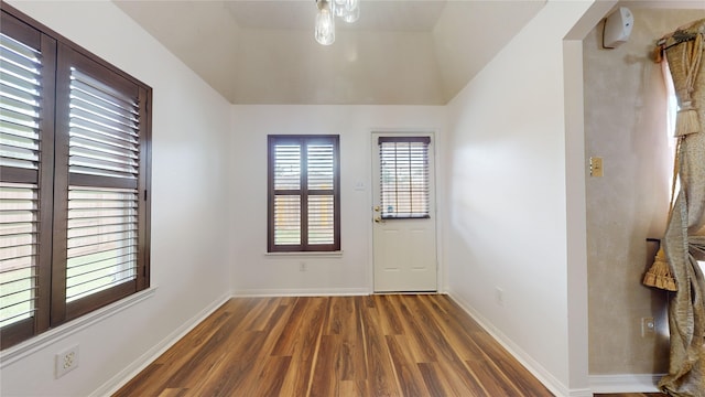 spare room with dark wood-type flooring and vaulted ceiling