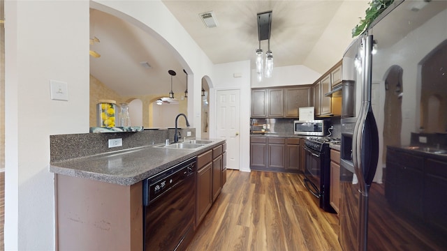 kitchen featuring sink, backsplash, pendant lighting, lofted ceiling, and black appliances