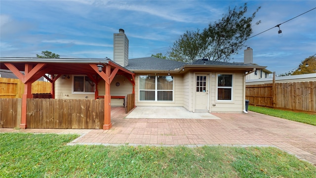 back of house featuring a lawn and a patio area