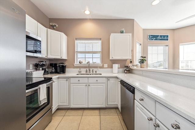 kitchen featuring sink, white cabinets, light tile patterned flooring, and appliances with stainless steel finishes