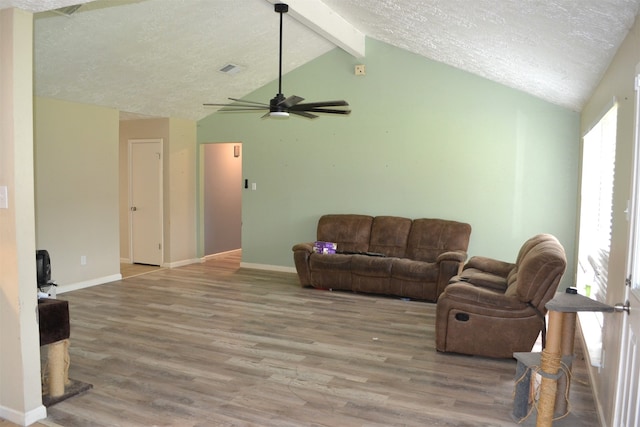 living room with lofted ceiling with beams, hardwood / wood-style floors, ceiling fan, and a textured ceiling