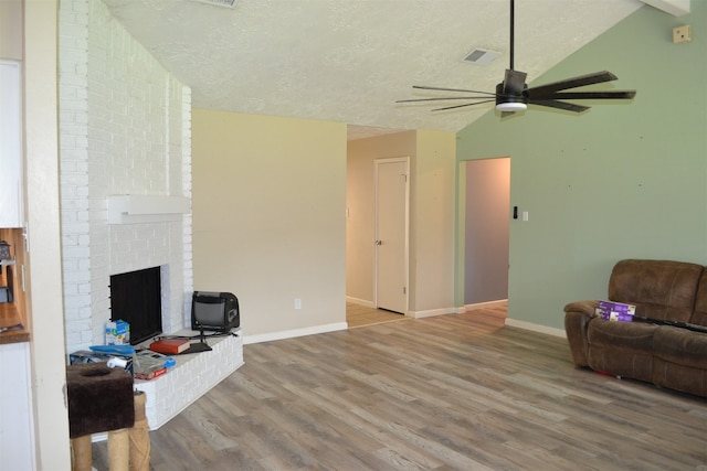 living room with a fireplace, wood-type flooring, ceiling fan, and vaulted ceiling